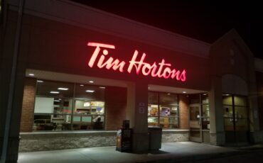 A Tim Hortons restaurant is brightly illuminated at night.