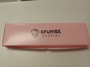 A pink box with the word crumbl cookies on it, showcasing fresh and delicious treats.