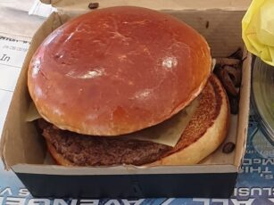 A burger sitting in a box on a table.