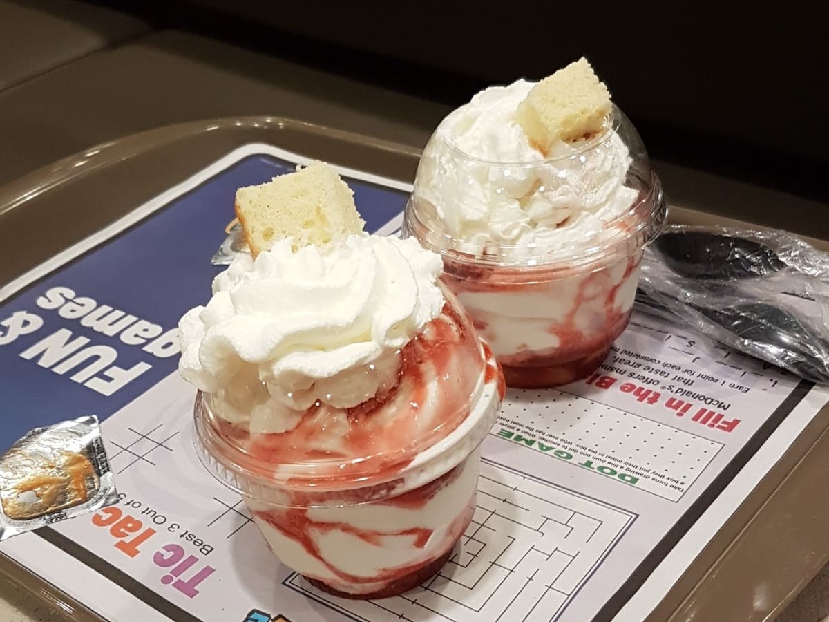 Two cups of strawberry ice cream on a tray.
